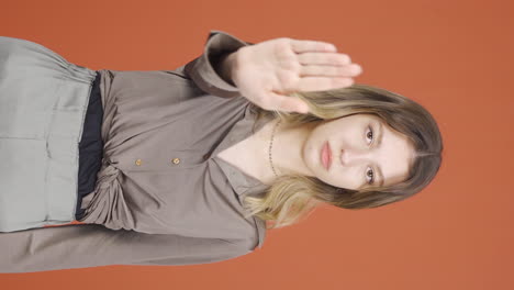 Vertical-video-of-Young-woman-making-stop-sign-for-camera.